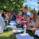 Schüler sitzen konzentriert auf dem Rasen und musizieren