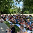 Schüler sitzen konzentriert auf dem Rasen und musizieren