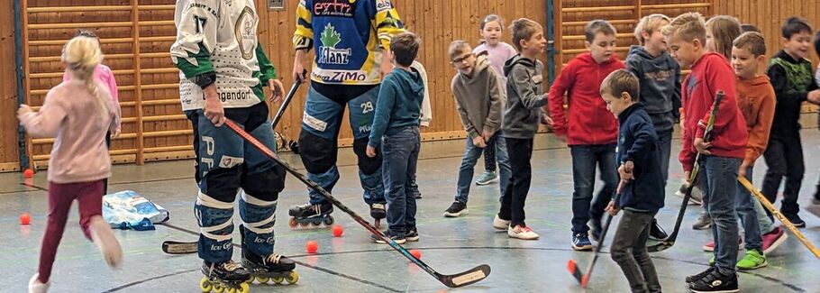 Den Schülern wird in der Turnhalle Indoorhockey vorgestellt